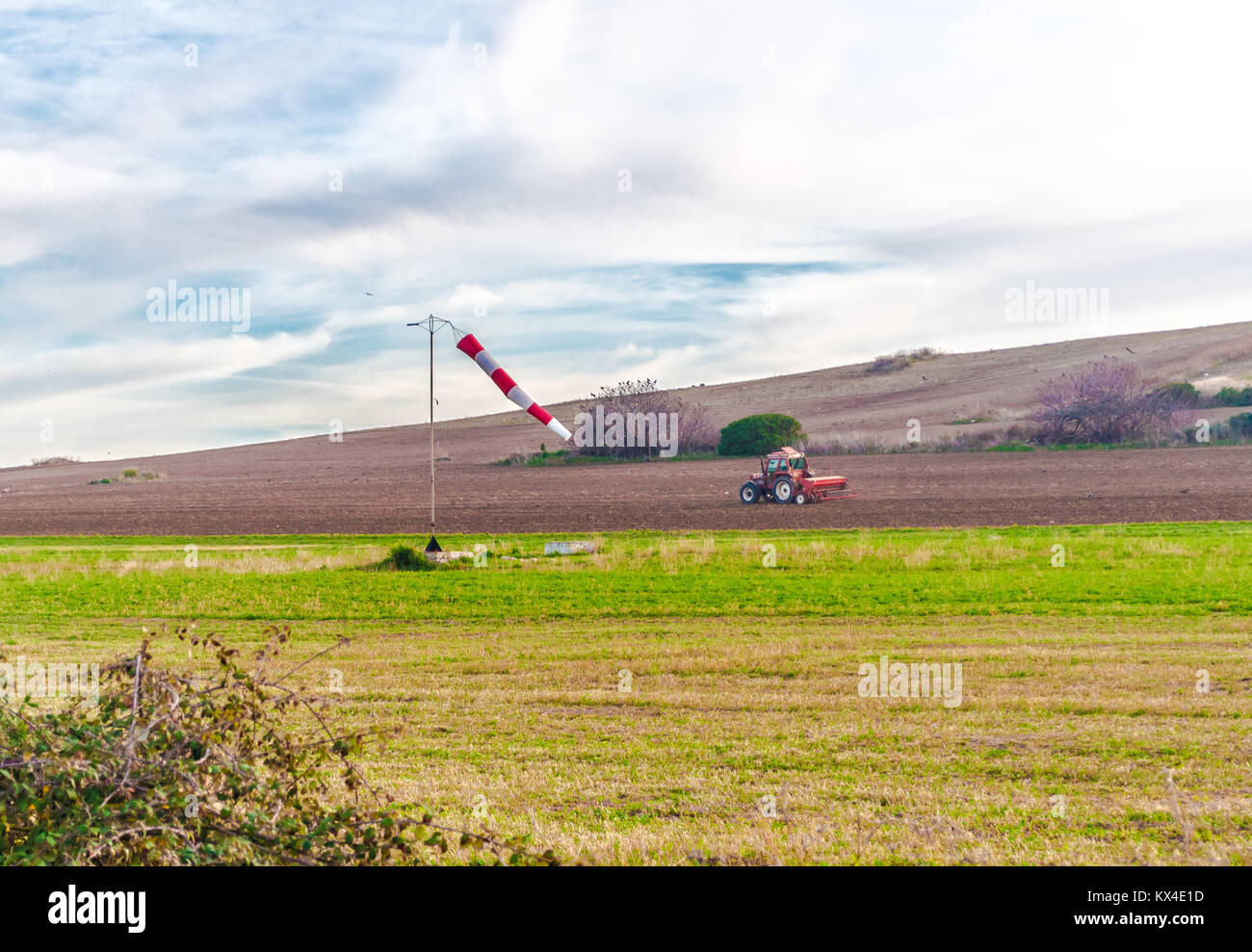 Windsock in the country in a cloudy day with a tractor working on background Stock Photo