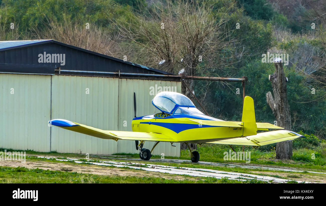 Small yellow airplane near its garage in country airport Stock Photo