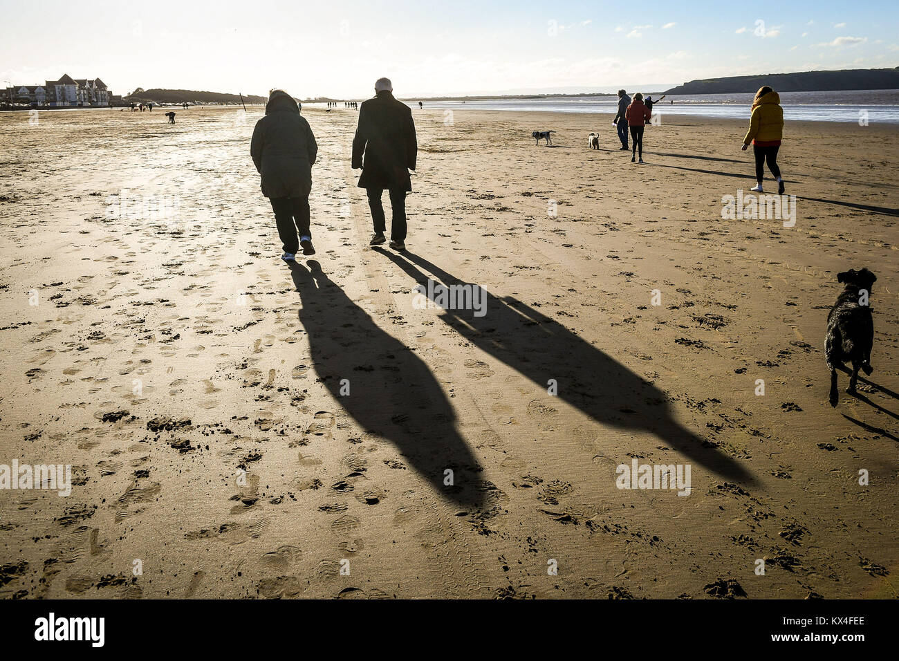 People cast long shadows on Weston-super-Mare Beach, Somerset, as temperatures plummet across the UK. Stock Photo