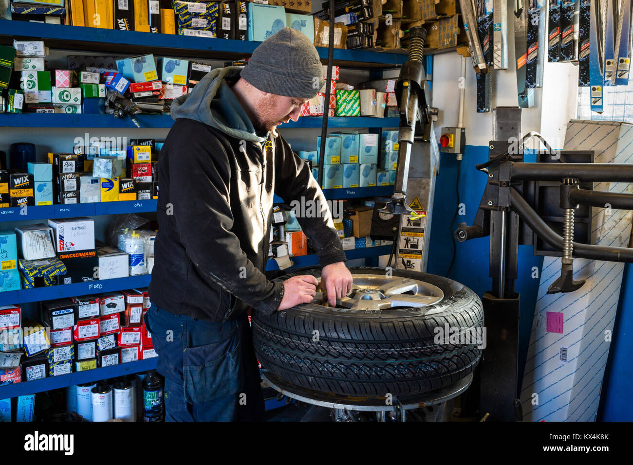 Apprentice Mechanic repairing a flat tyre with a compressor in garage Stock Photo