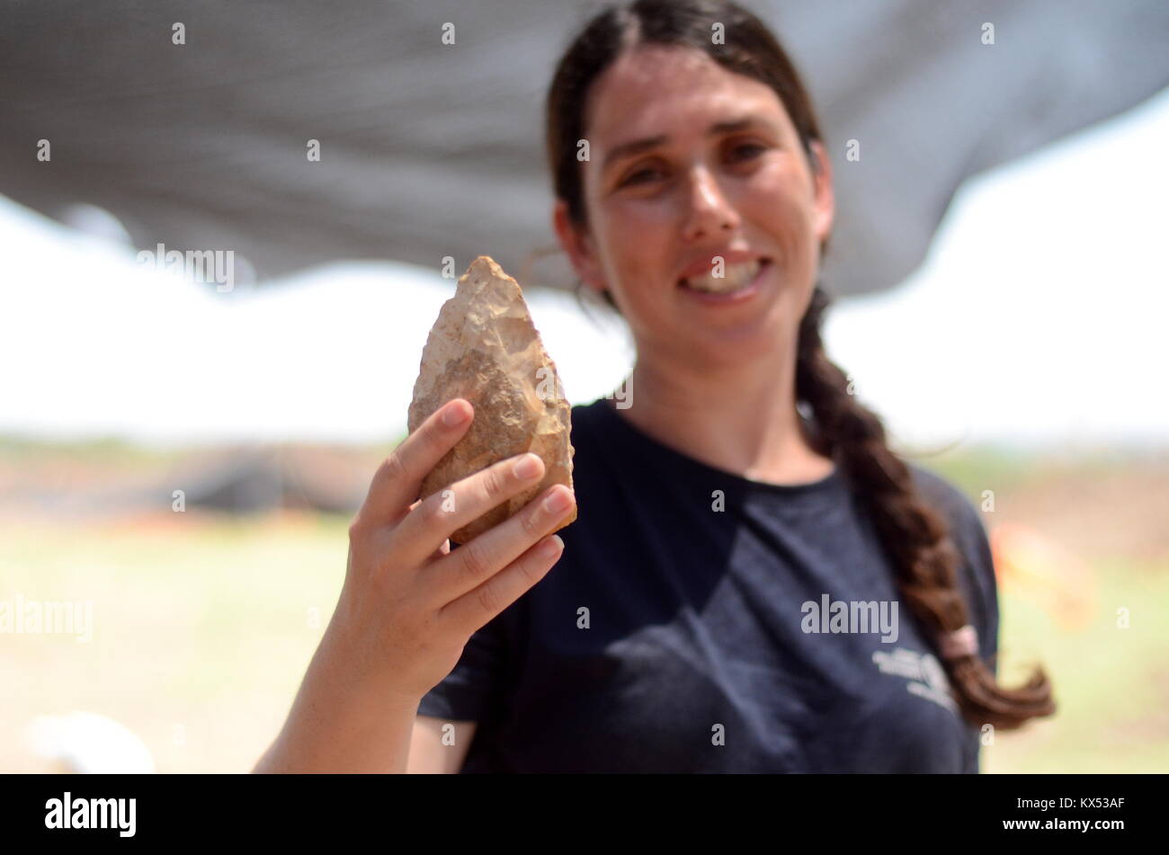 Jaljulia, Israel. 25th June, 2017. HANDOUT - An undated handout image dated shows excavation leader Maajan Schemer of the Israel Antiquities Authority holding a flint hand axe in Jaljulia, Israel. - NO WIRE SERVICE - (ATTENTION EDITORS: FOR EDITORIAL USE ONLY IN CONNECTION WITH CURRENT REPORTING/MANDATORY CREDIT: PHOTO: Credit: Samuel Magal/Israel Antiquities Authority/dpa/Alamy Live News Stock Photo