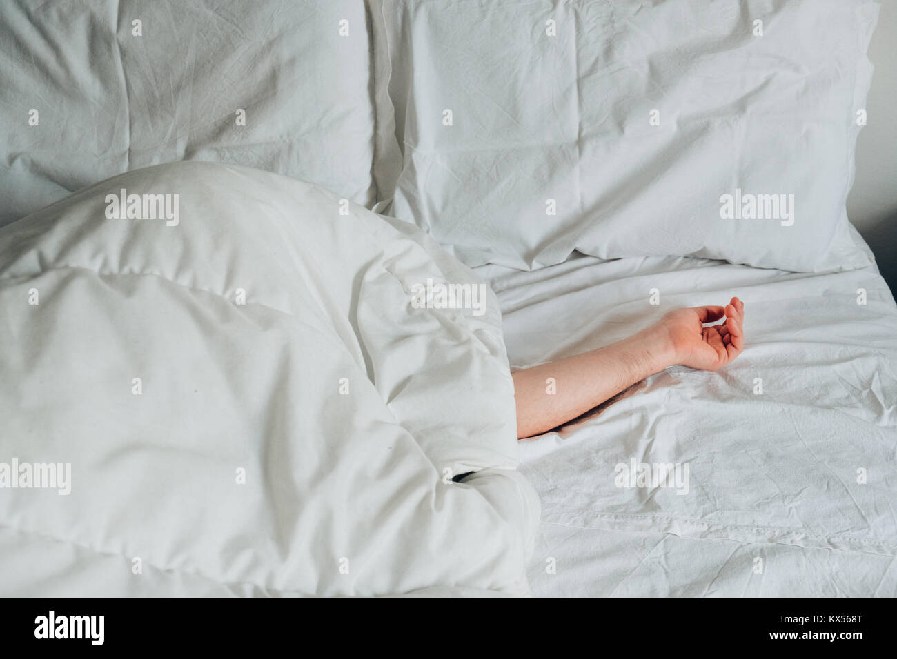 Laziness concept. Hand on a white bed sheet in the morning Stock Photo