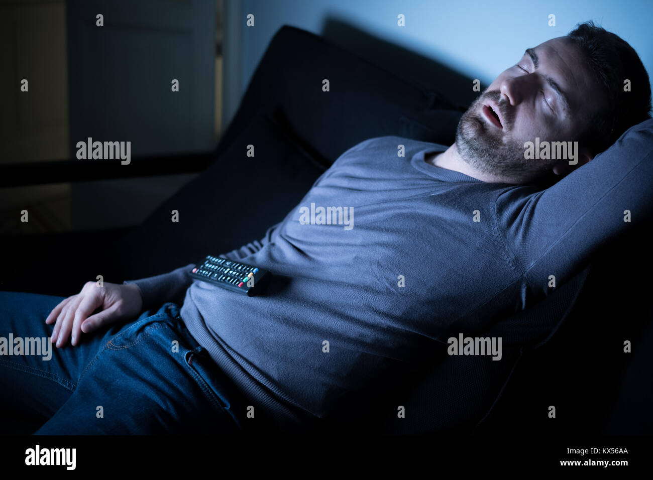 Man sleeping on the couch in front of television screen Stock Photo Alamy