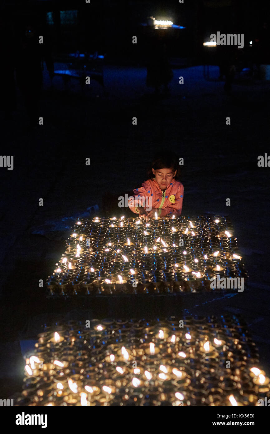Tibetan girl lighting buddhist candles, Boudhanath, Kathmandu, Nepal Stock Photo