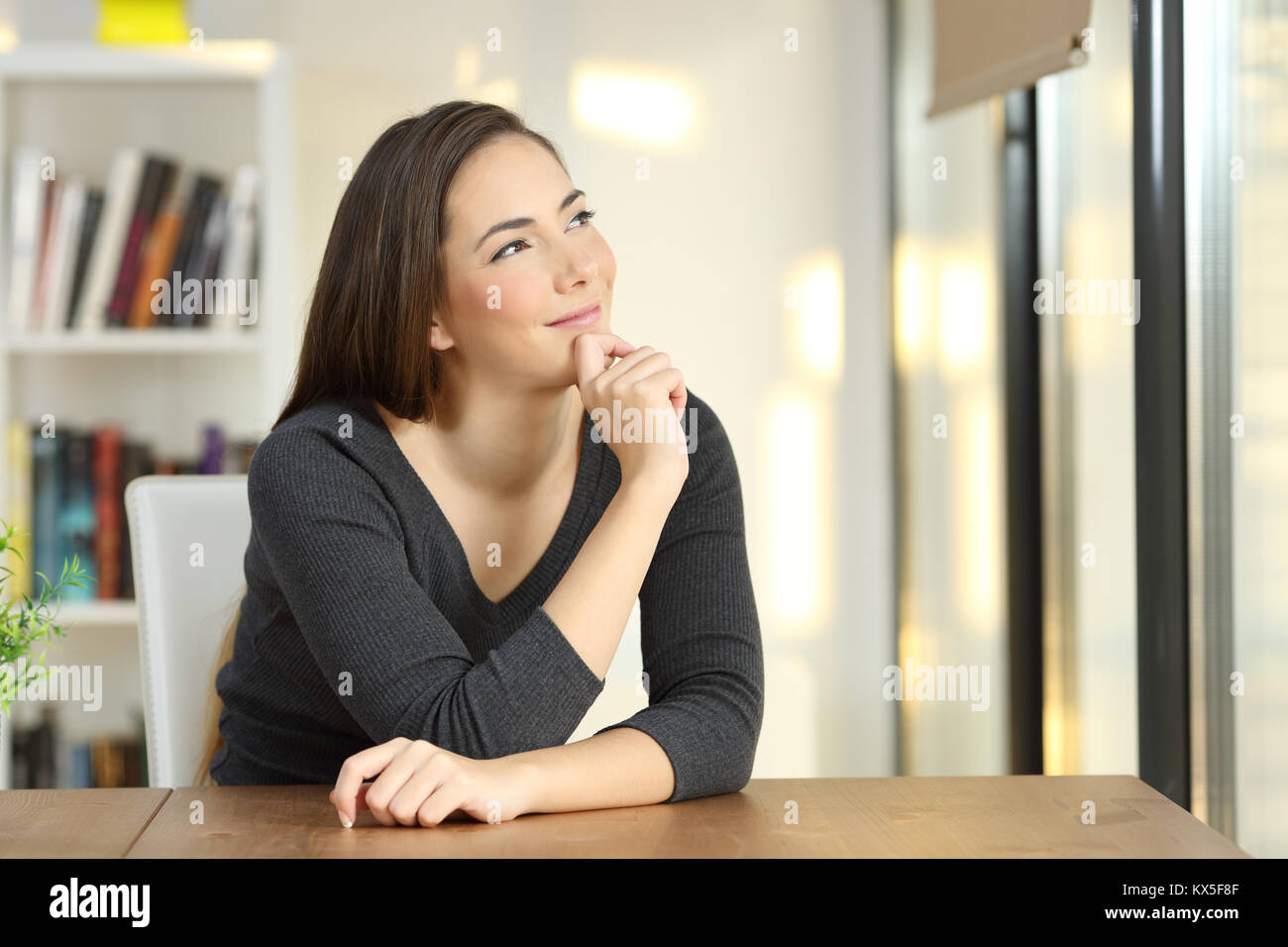 Portrait of a dreamer woman wondering in the living room at home Stock Photo