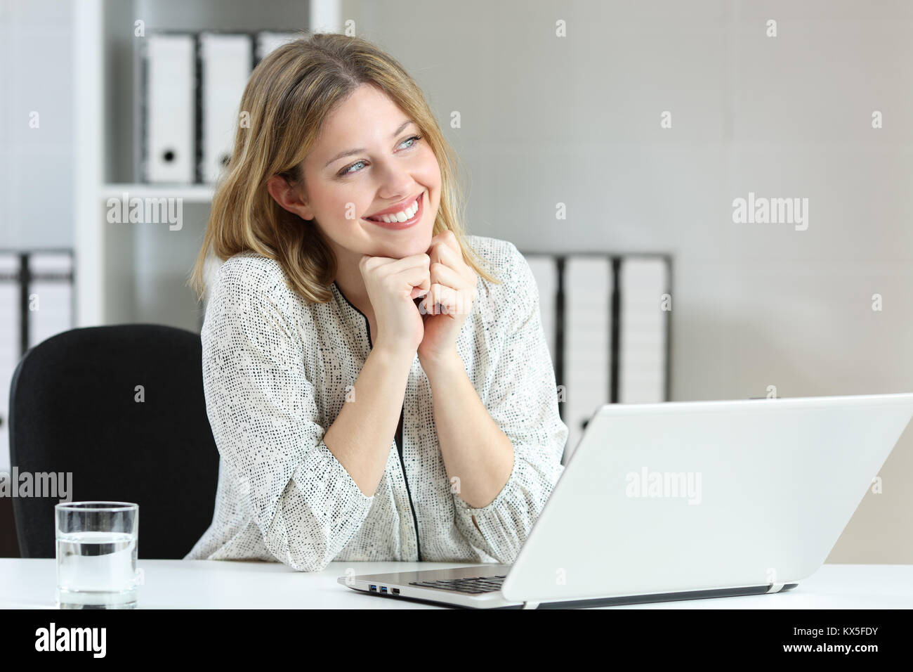 Portrait of an office worker dreaming and looking at side sitting in a desktop at workplace Stock Photo