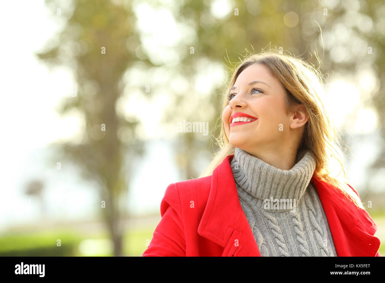 Portrait of a funny woman wearing red jacket looking above outdoors in