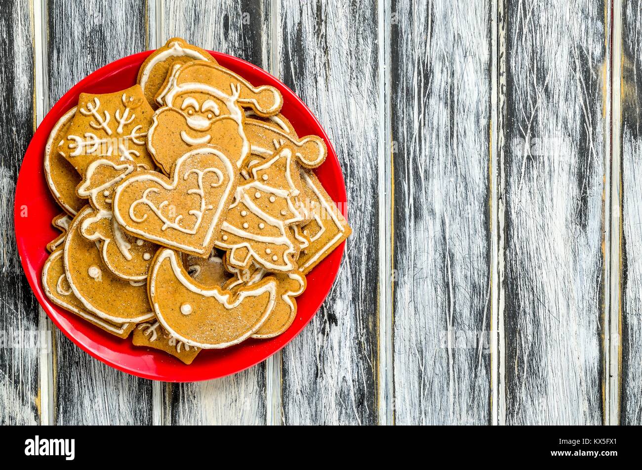Sweet Christmas pastries. Spicy gingerbreads on red on a plate on a wooden table. Stock Photo