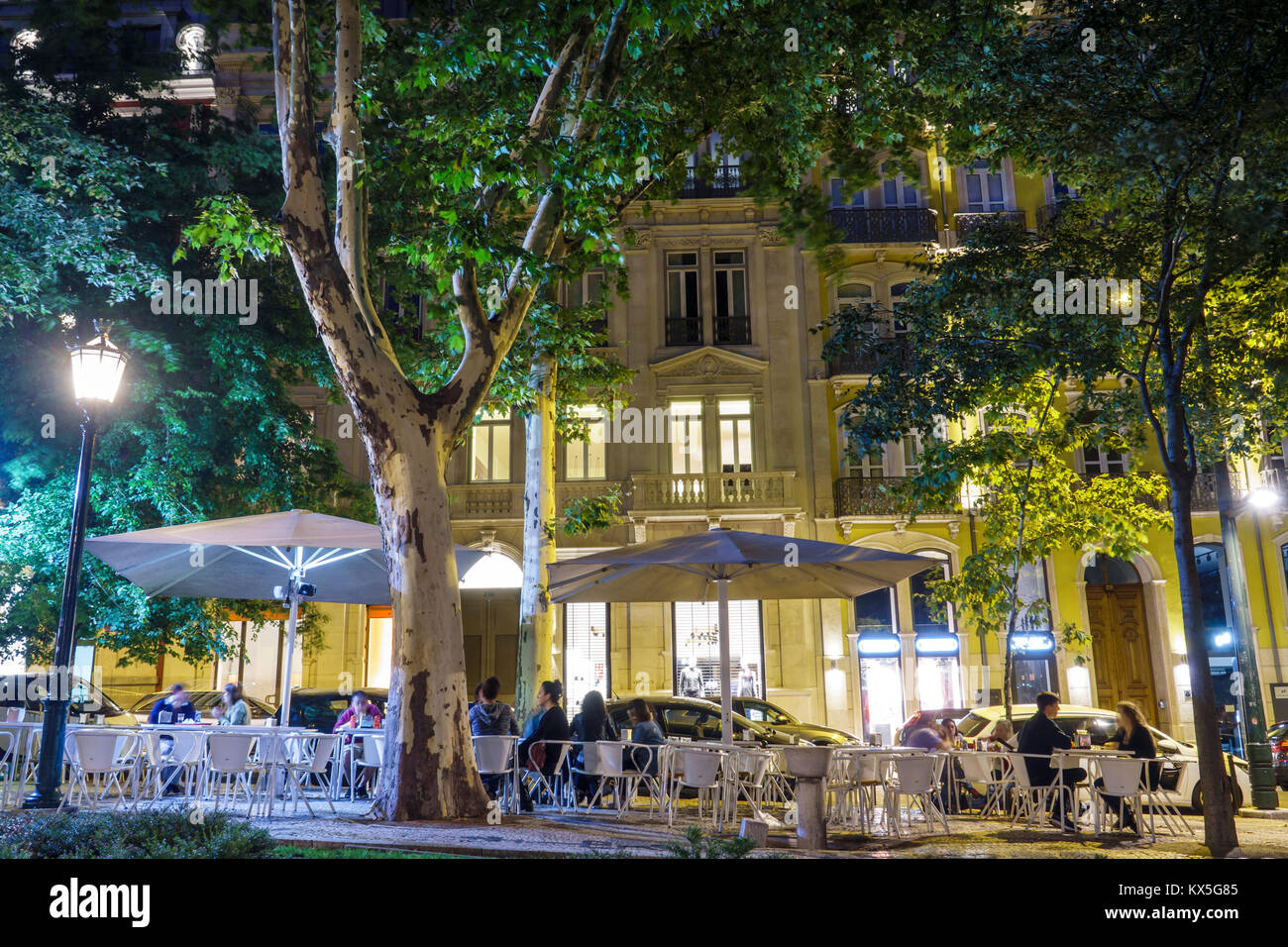 Lisbon Portugal,Avenida da Liberdade,promenade,Bananacafe,al fresco,sidewalk outside tables dining street,tables,umbrellas,evening,lighting,trees,Hisp Stock Photo