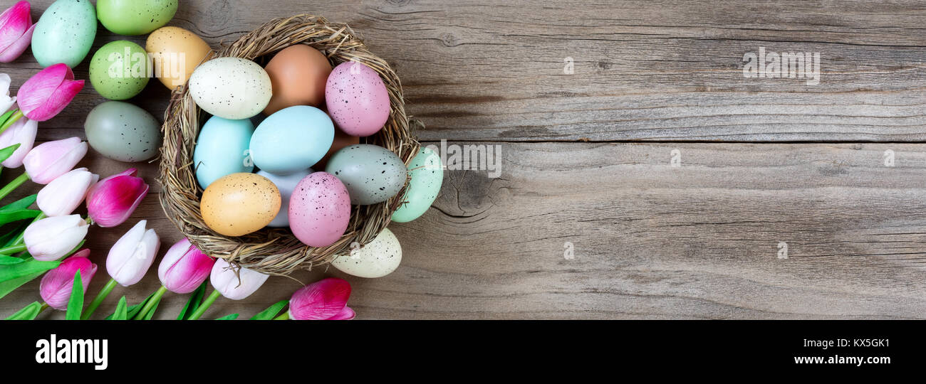 Tulips and colorful eggs in nest on rustic wooden boards for Easter ...