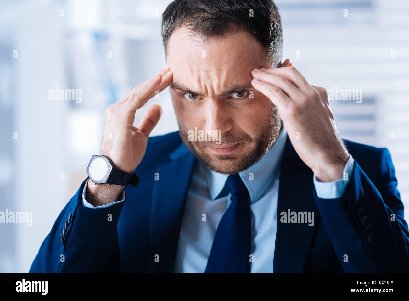 Busy hardworking man touching his head while thinking and looking concentrated Stock Photo