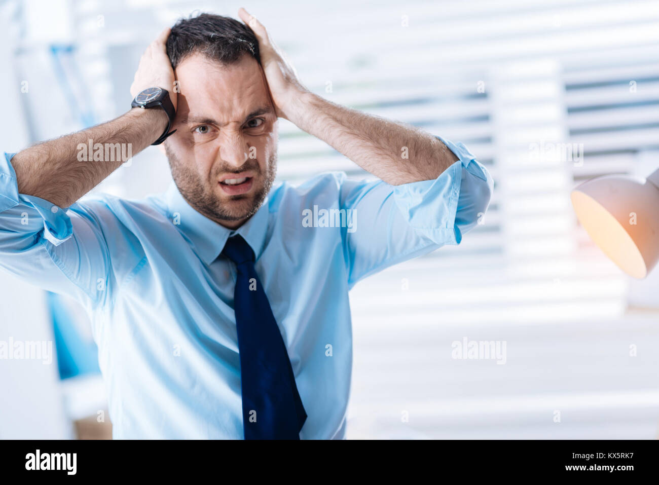 Unhappy bearded man holding his head and expressing his negative feelings Stock Photo