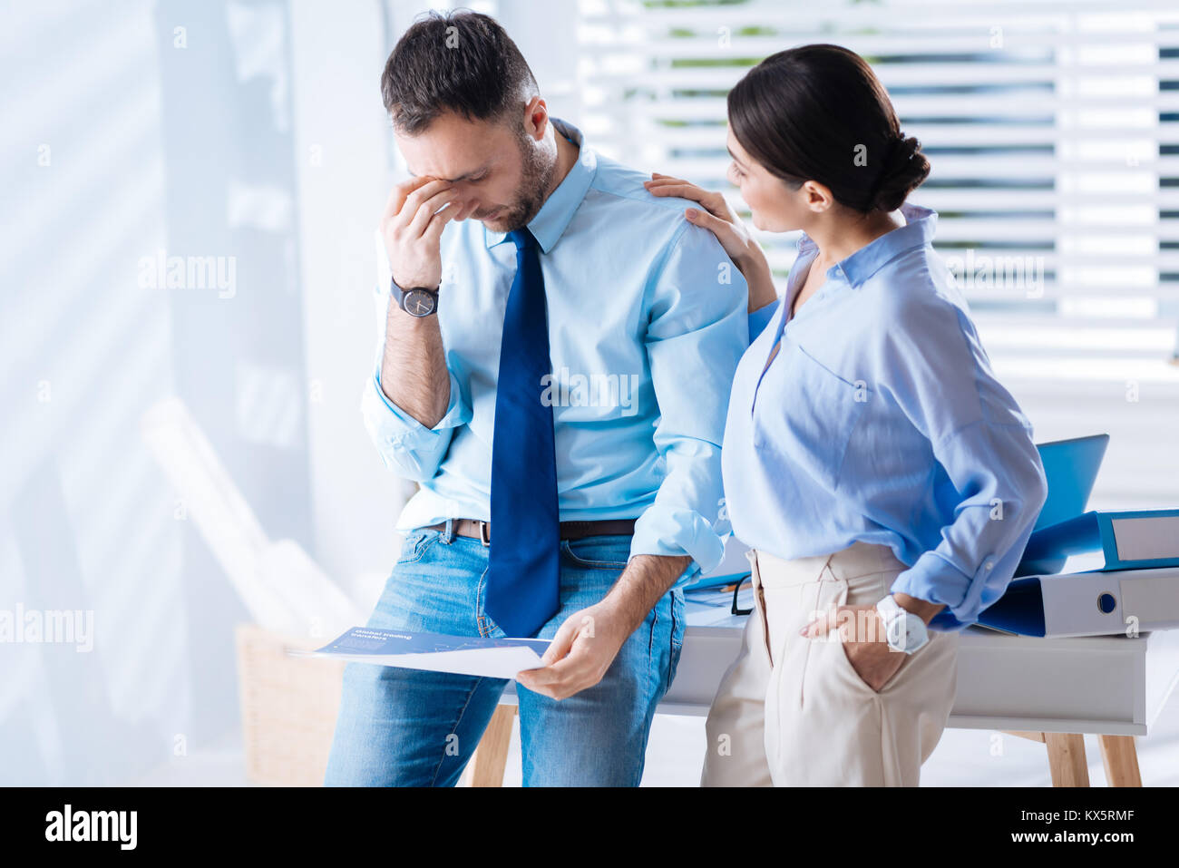 Tired man touching his forehead while a kind woman comforting him Stock Photo