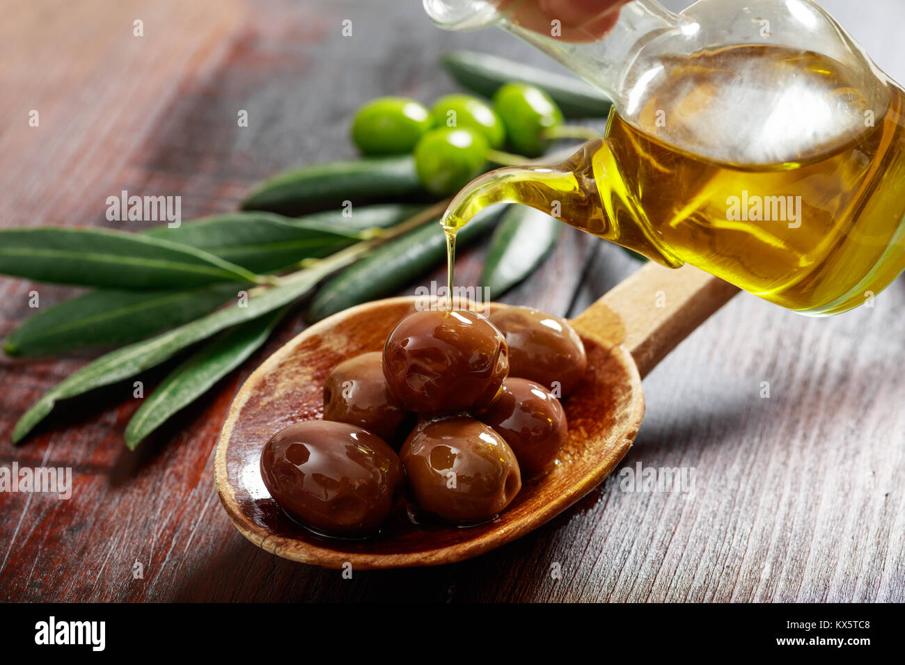 Olives in a wooden spoon and olive oil Stock Photo - Alamy