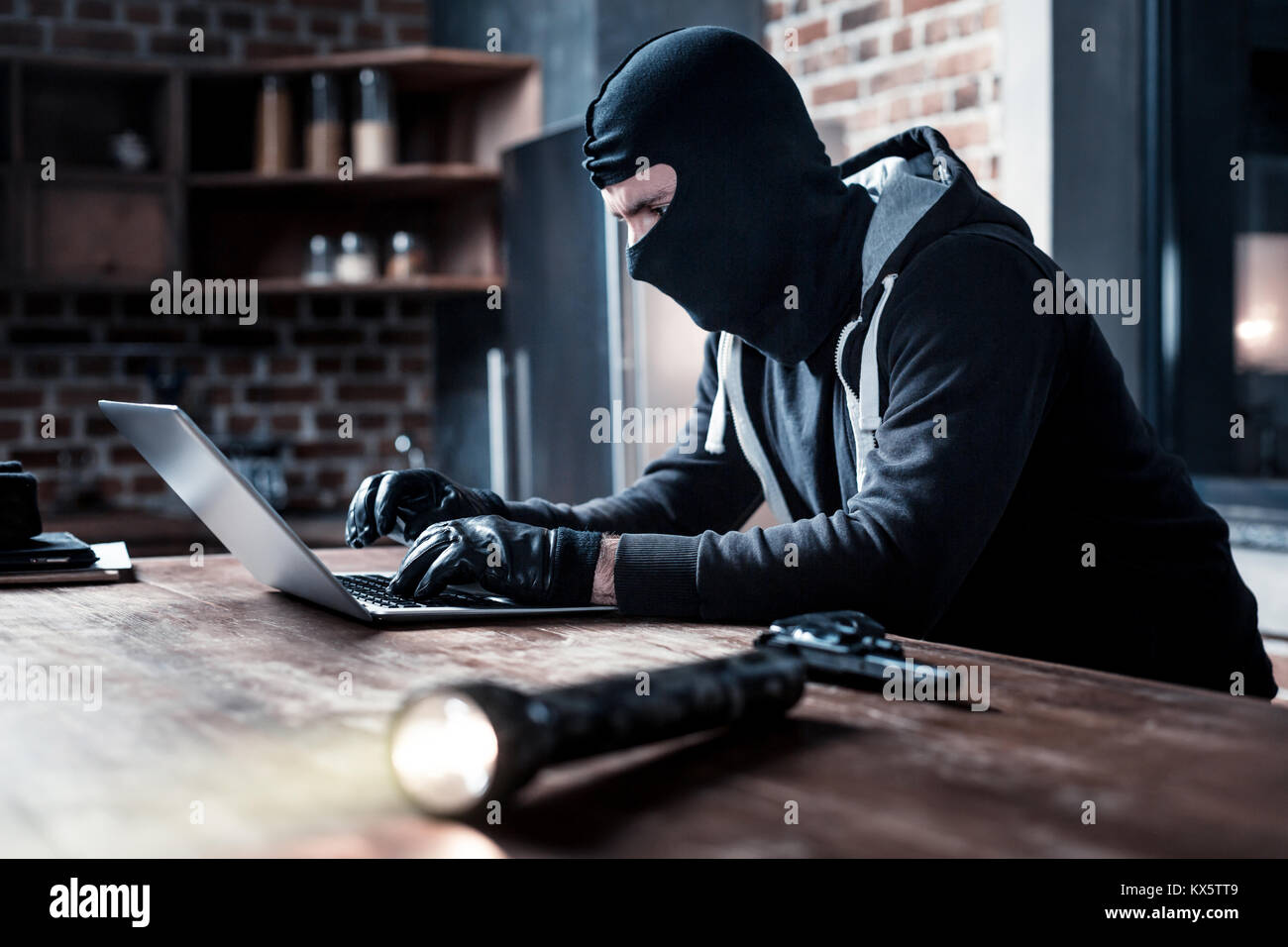 Masked computer hacker typing on the laptop Stock Photo - Alamy