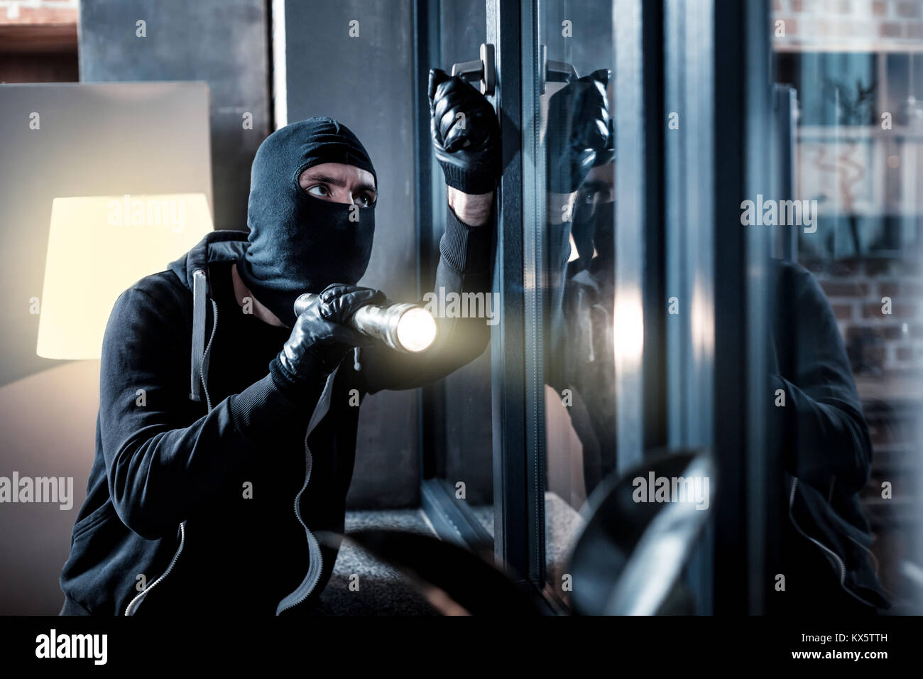 Masked burglar breaking into the house Stock Photo