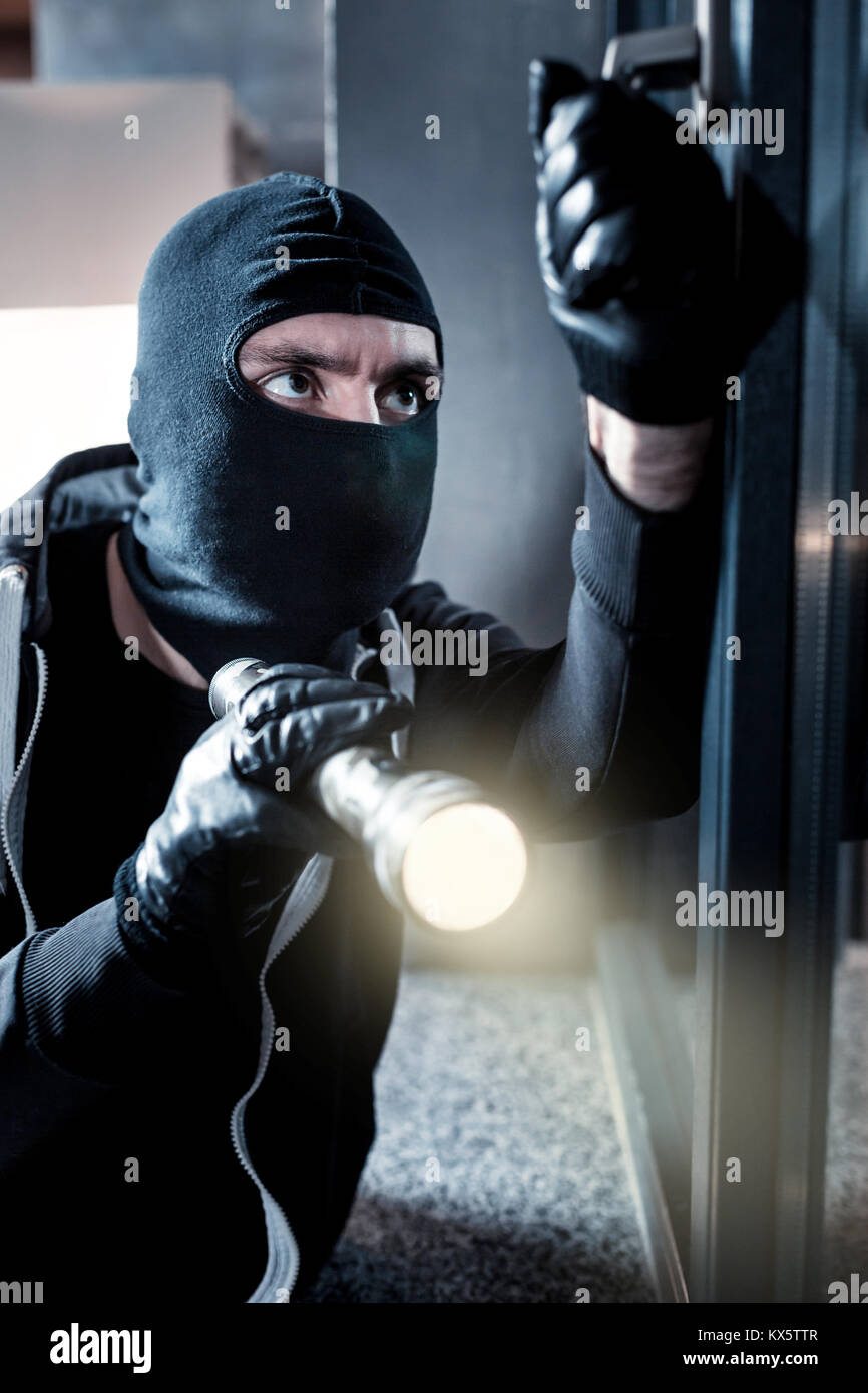 Masked thief breaking into the house Stock Photo