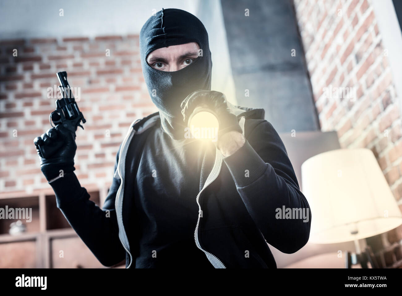 Enraged criminal holding a gun and a torch Stock Photo