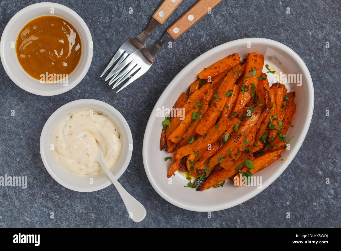 Healthy baked sweet potato fries with curry and creamy garlic sauces
