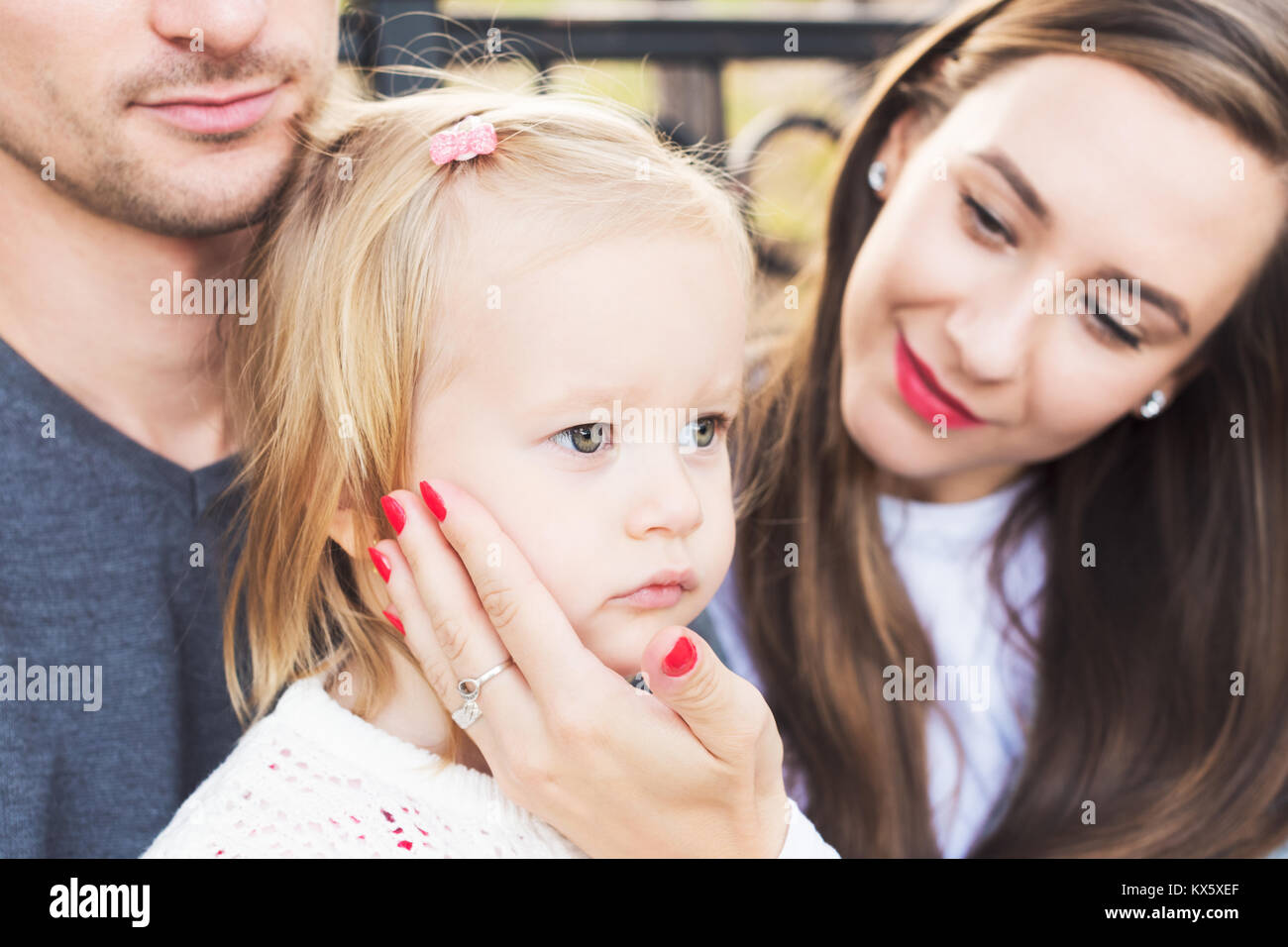 Young loving family of three, authentic candid outdoors family portrait