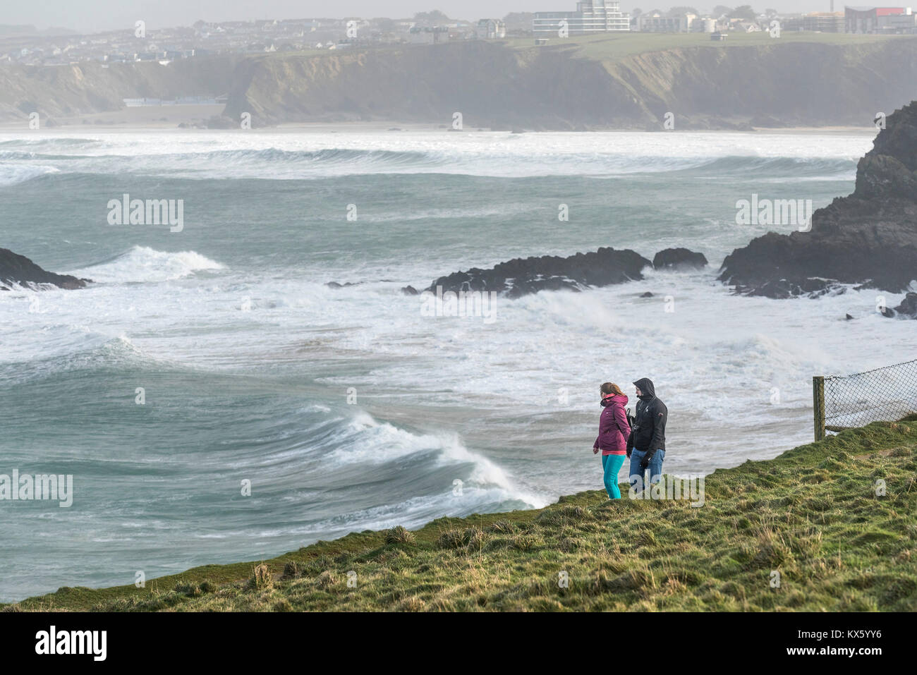 Two walkers on the coastal path during stormy weather in Newquay Cornwall. Stock Photo