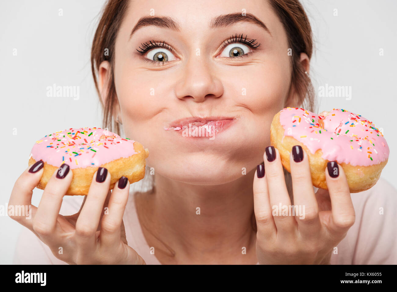 Close up portrait of a satisfied pretty girl eating donuts isolated over white background Stock Photo
