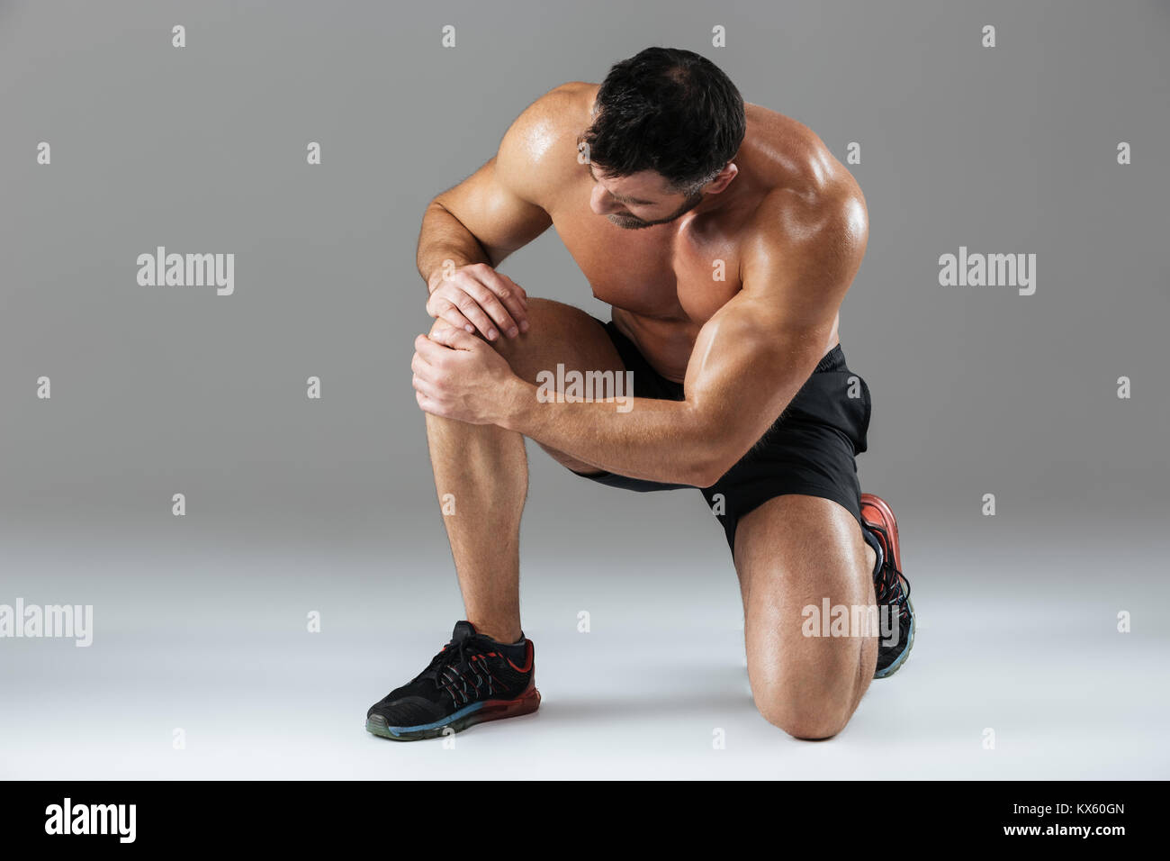 Portrait of a strong muscular male bodybuilder suffering from a knee ...
