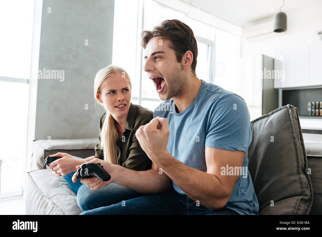 Man beating woman at video games with controller on console over blue  background. Boyfriend celebrating win and girlfriend feeling disappointed  about losing online gameplay in studio Stock Photo - Alamy