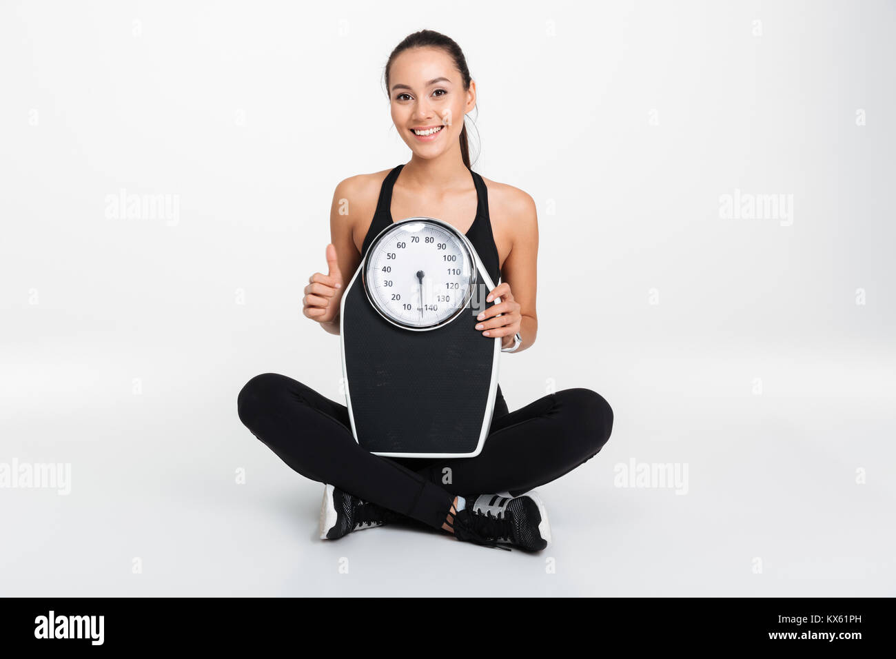 Portrait of a happy asian fitness woman holding weight scales and ...