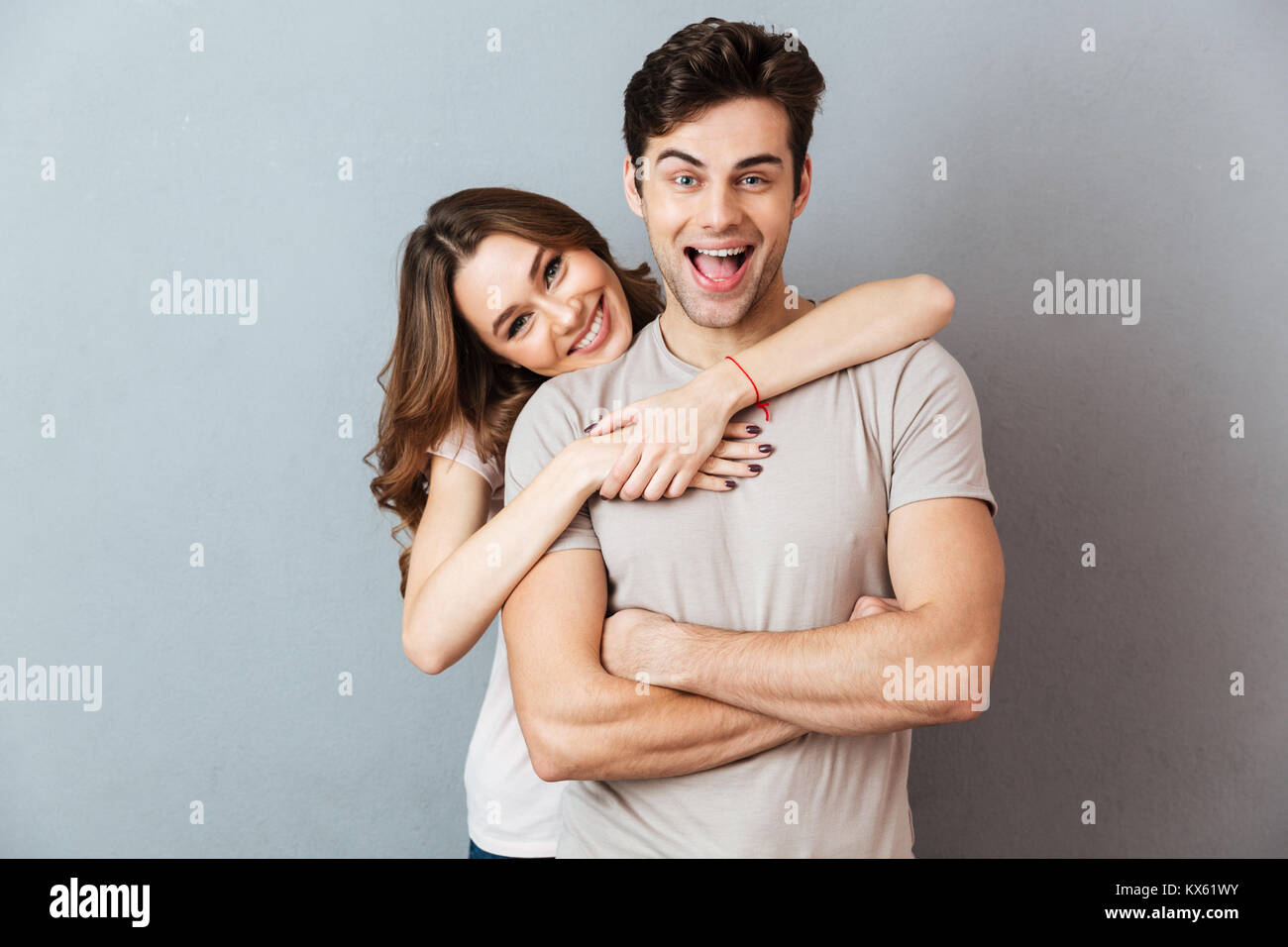 Portrait of a cheerful young couple hugging while standing and looking ...