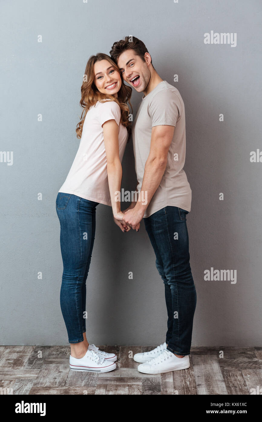 Full length portrait of a happy young couple holding hands and looking ...