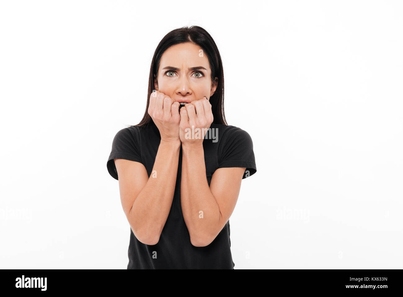 Portrait of a frightened woman holding hands at her face and looking at ...