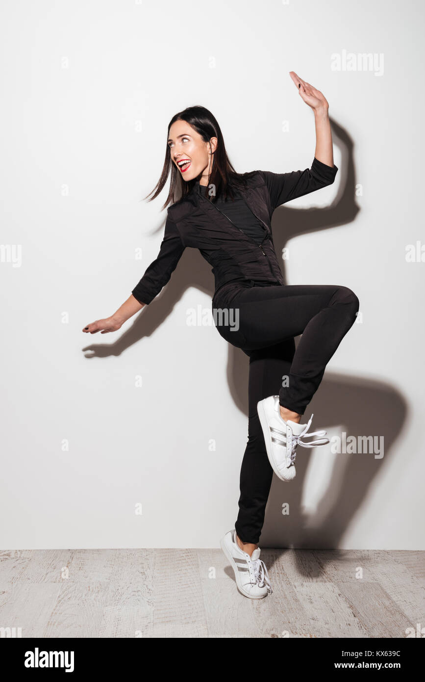 Full length portrait of a smiling casual woman posing while standing ...