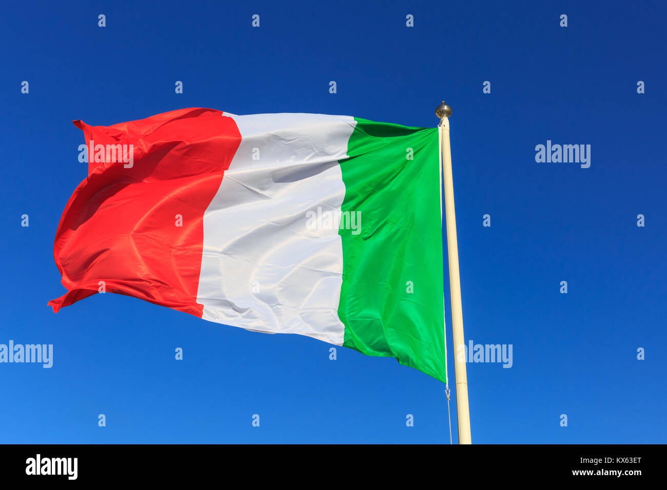 The Italian National flag flying on a pole against clear deep blue sky Stock Photo