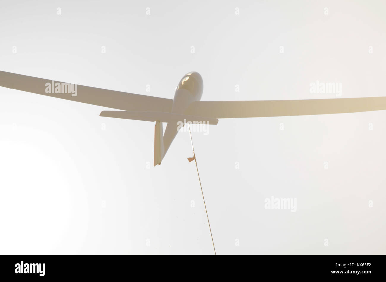 A winch launched glider soars into the sky and into the sunlight. The