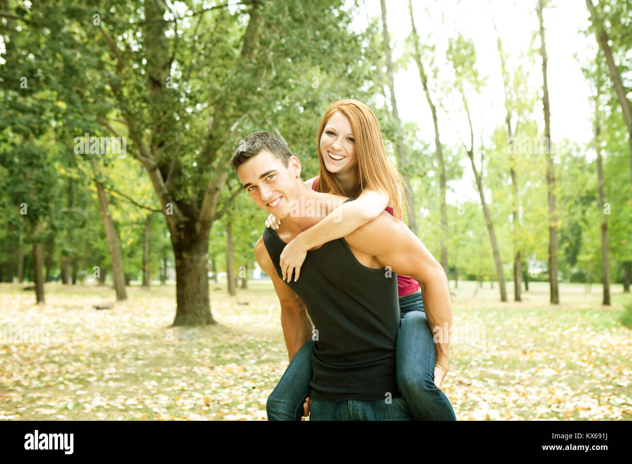 laughing young couple playing piggyback in the park Stock Photo - Alamy