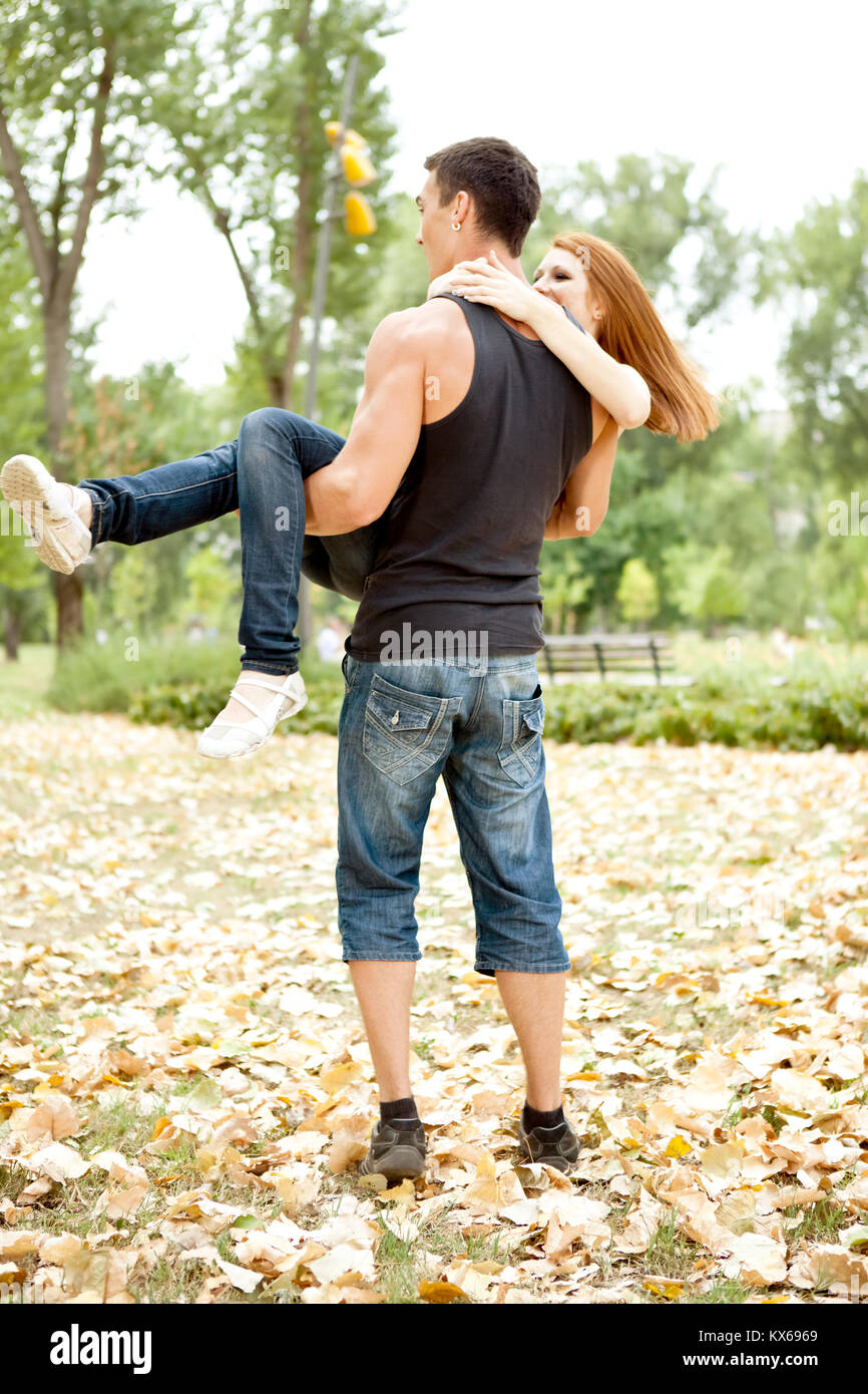 young couple in park having fun, man holding girl in arms Stock Photo ...