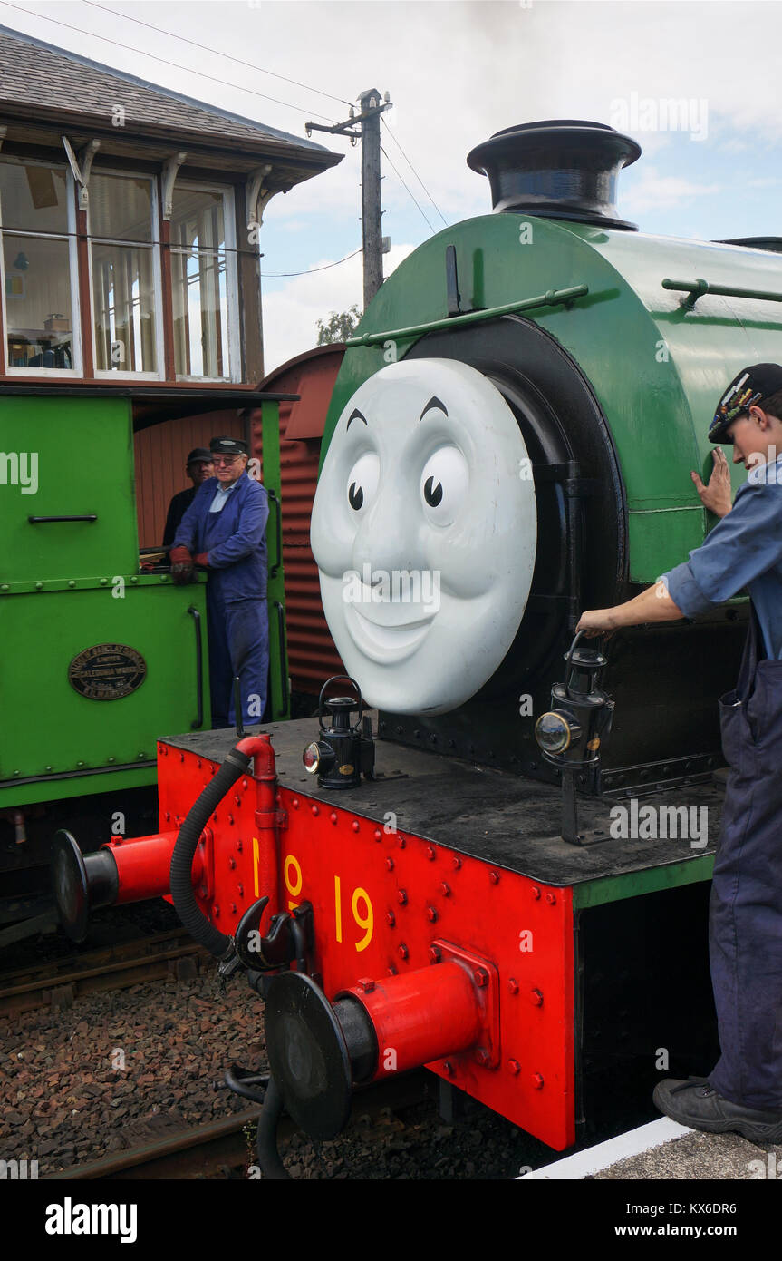 Railway workers on a green steam engine as part of a Thomas and Friends