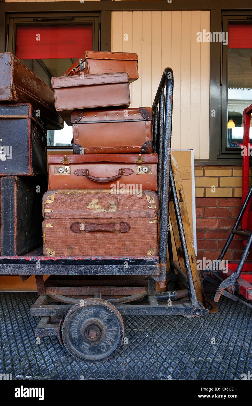 Black and brown vintage travel suitcases stacked on a railway trolley. Stock Photo
