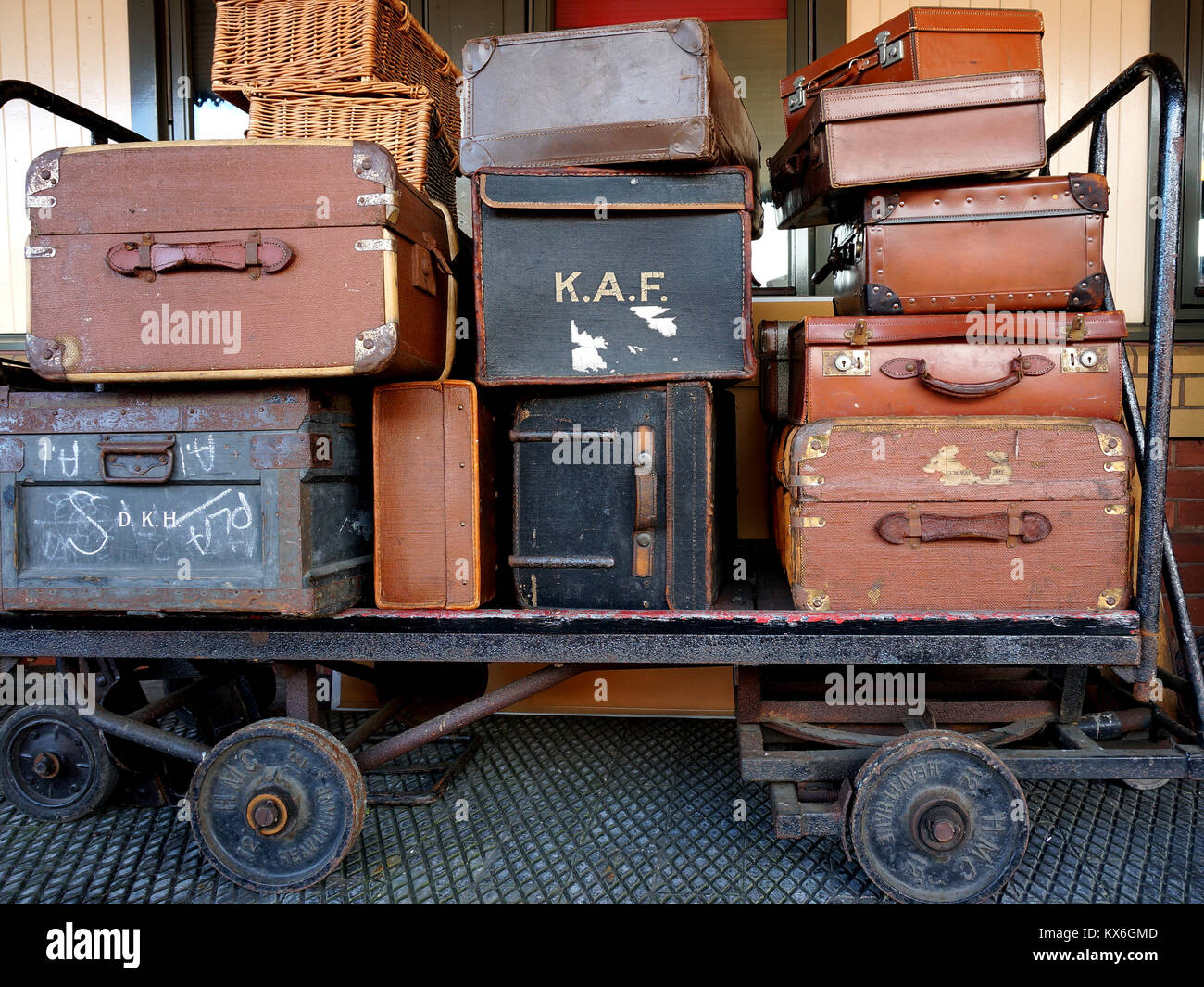 Black and brown vintage travel suitcases stacked on a railway trolley. Stock Photo