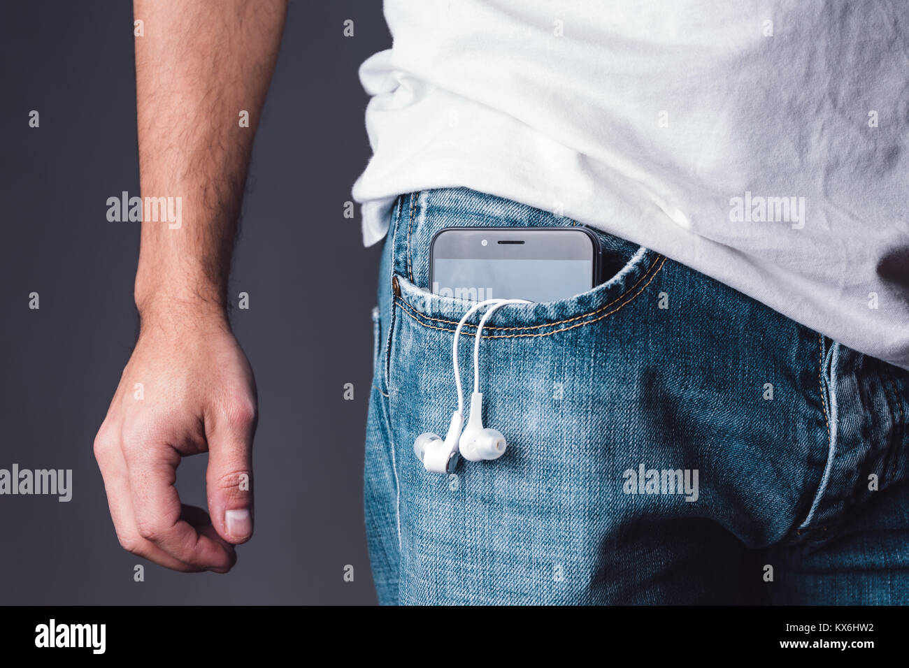 Smartphone with earphones on a caucasian young adult male jeans pocket. Stock Photo