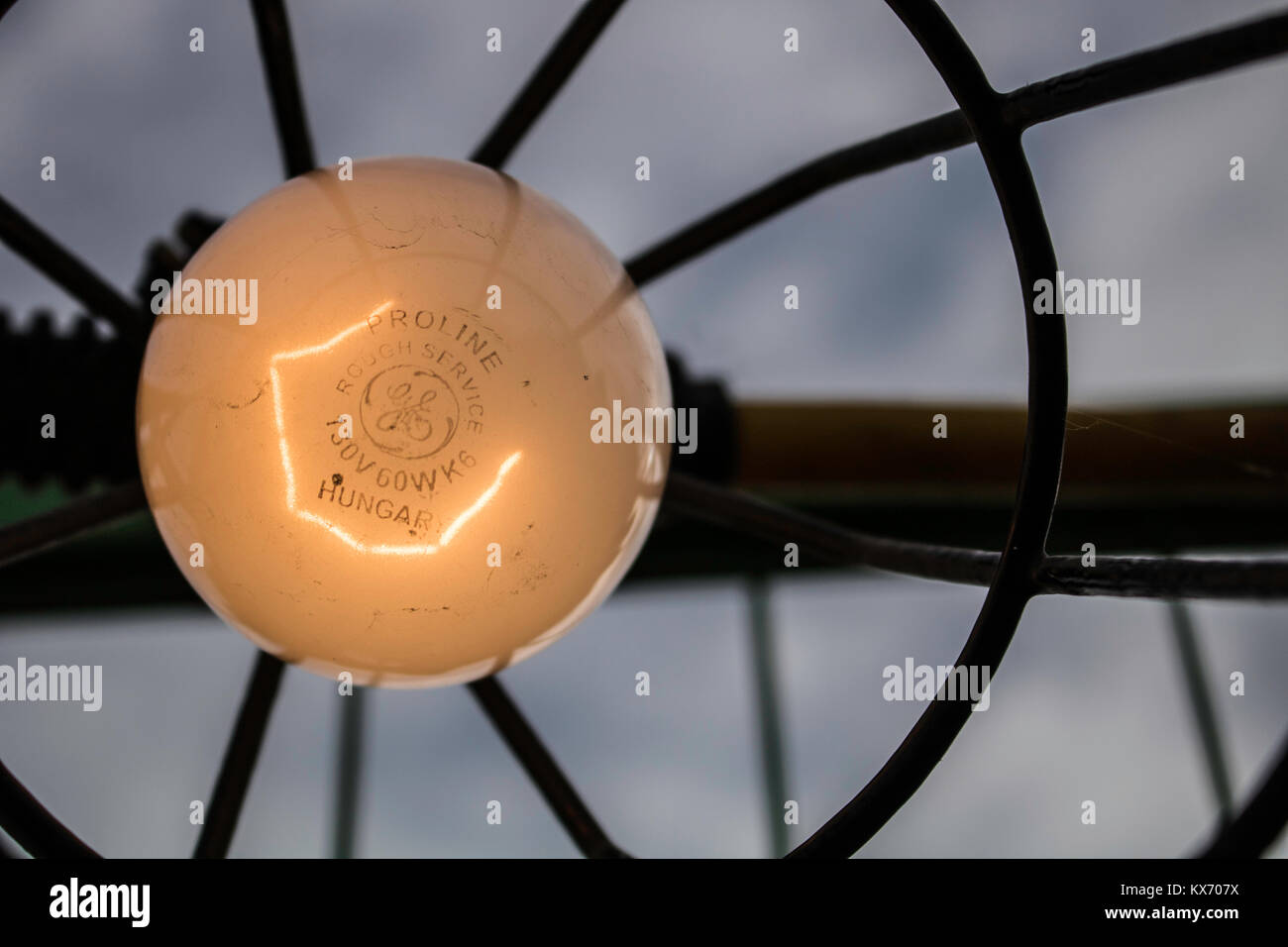 A lightbulb in the foreground with a moody sky in the background. Stock Photo