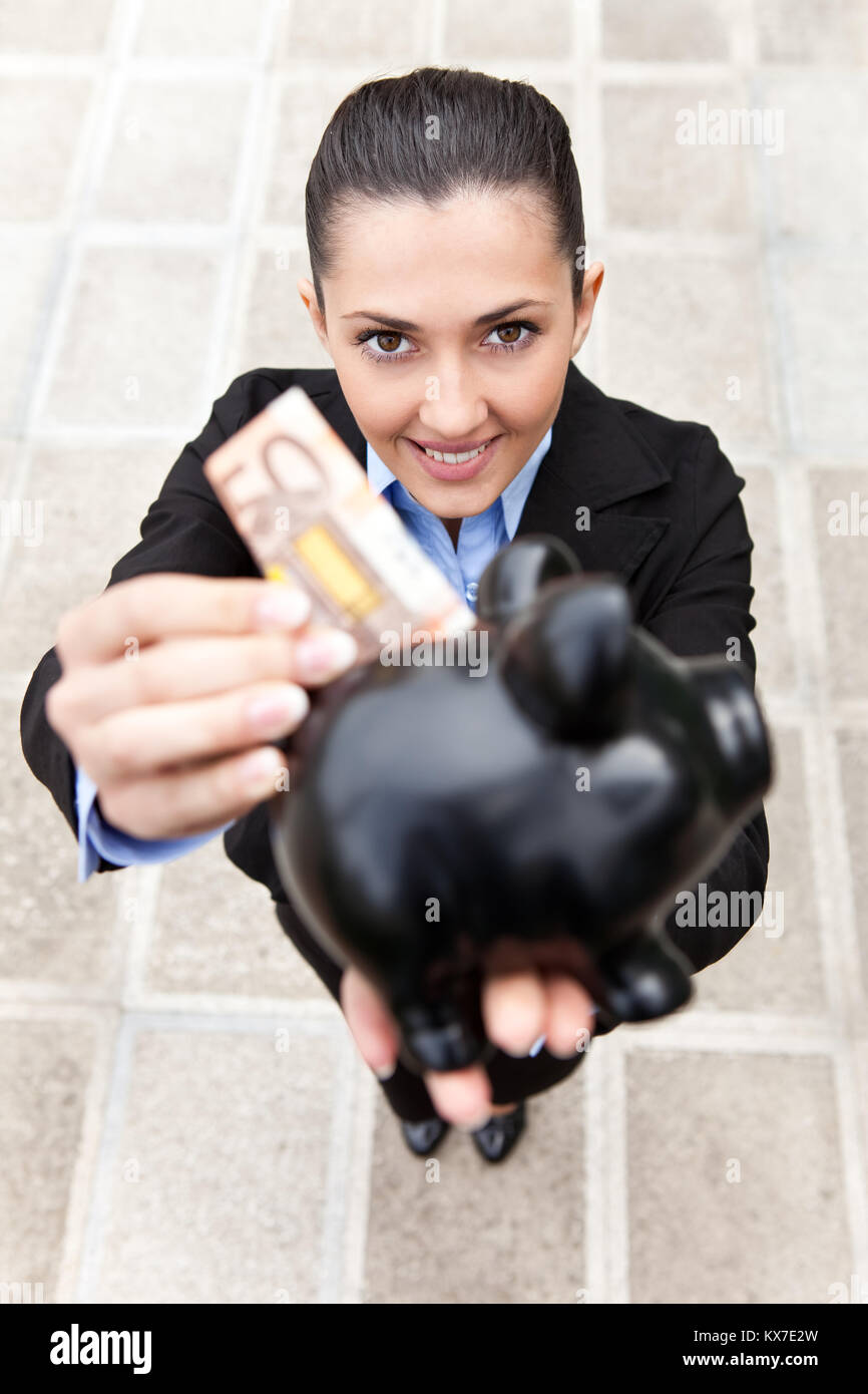 businesswoman holding a piggy bank, standing outdoor, top view Stock Photo