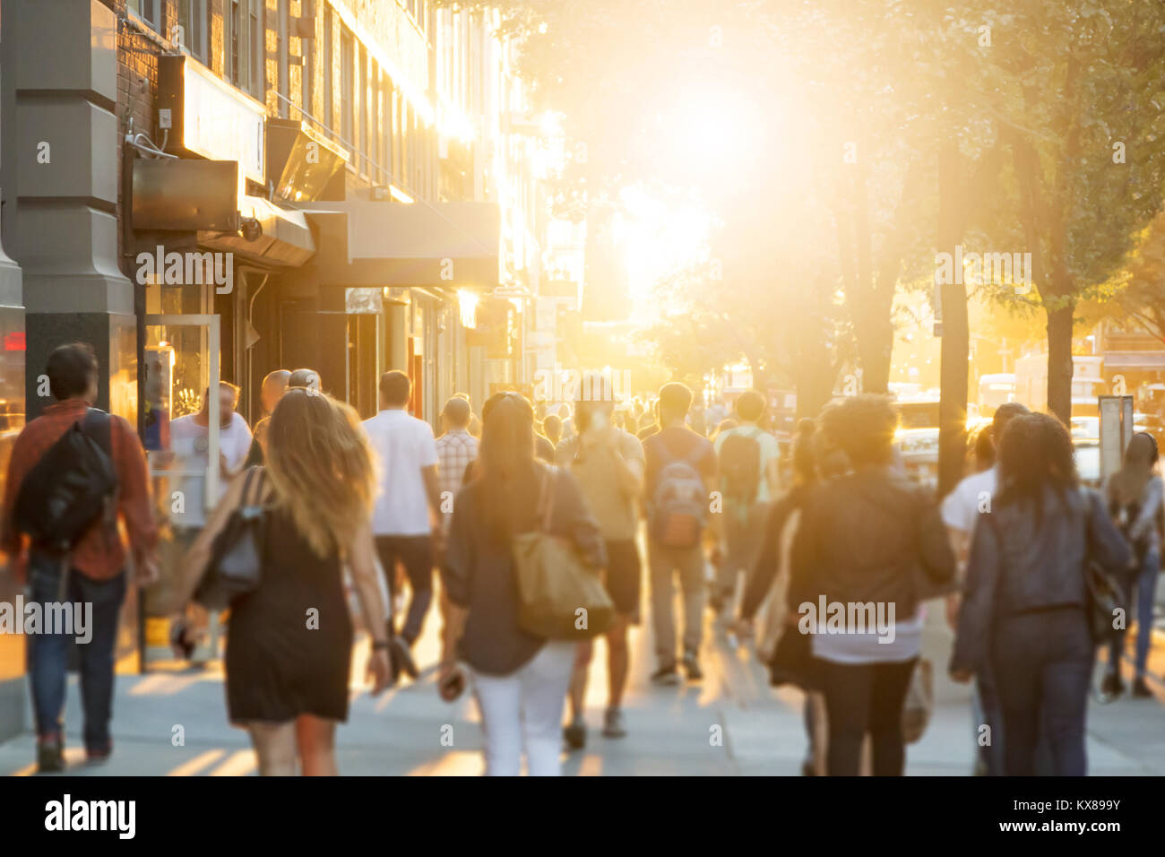 Crowd of anonymous men and women walking down an urban sidewalk with ...