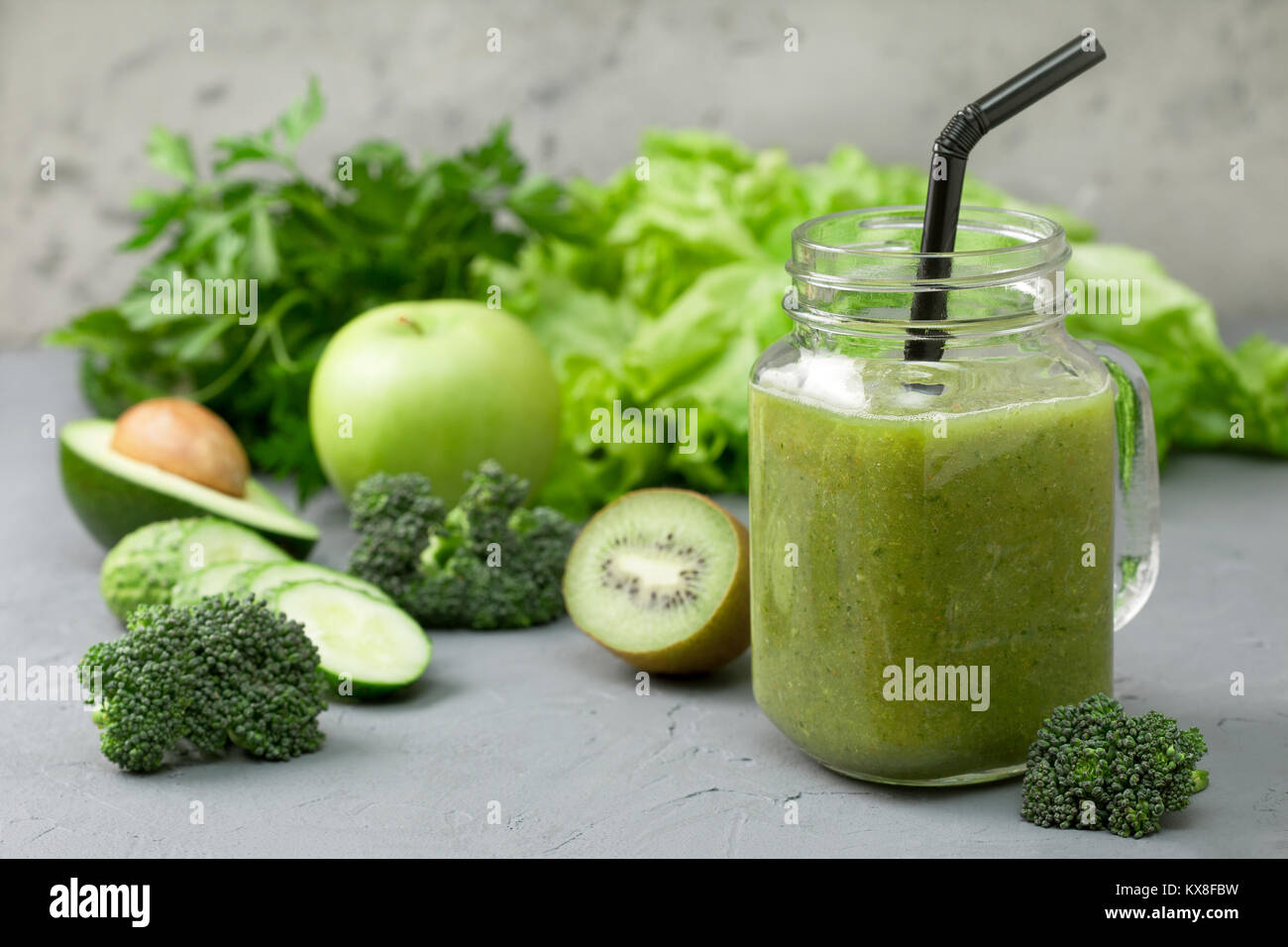 green smoothies in glass jar mason with fresh vegetables and herbs: broccoli, avocado, lime, celery, apple, kiwi, parsley. detox smoothies Stock Photo