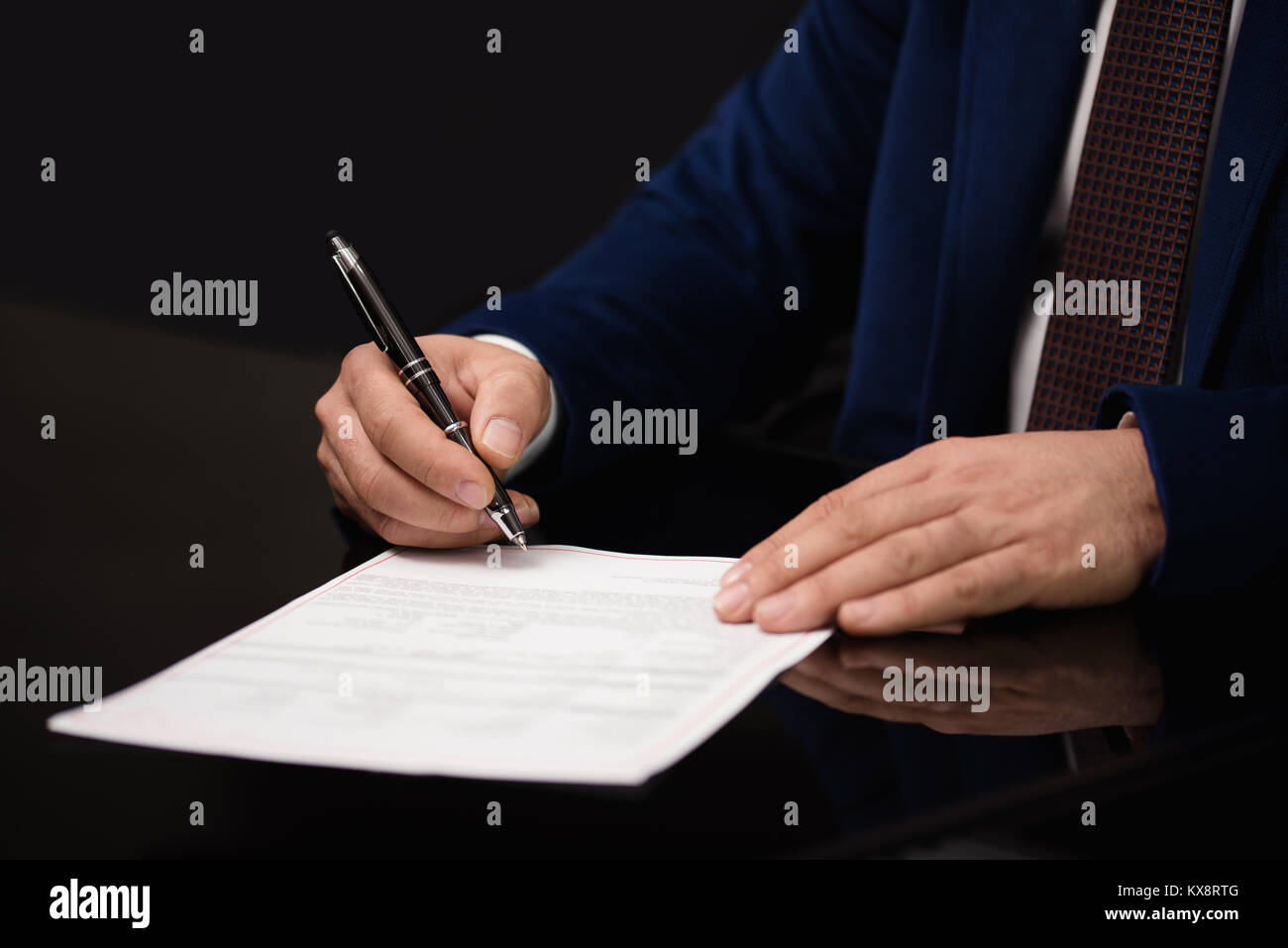 Close up of businessman sitting at table and signing document Stock Photo