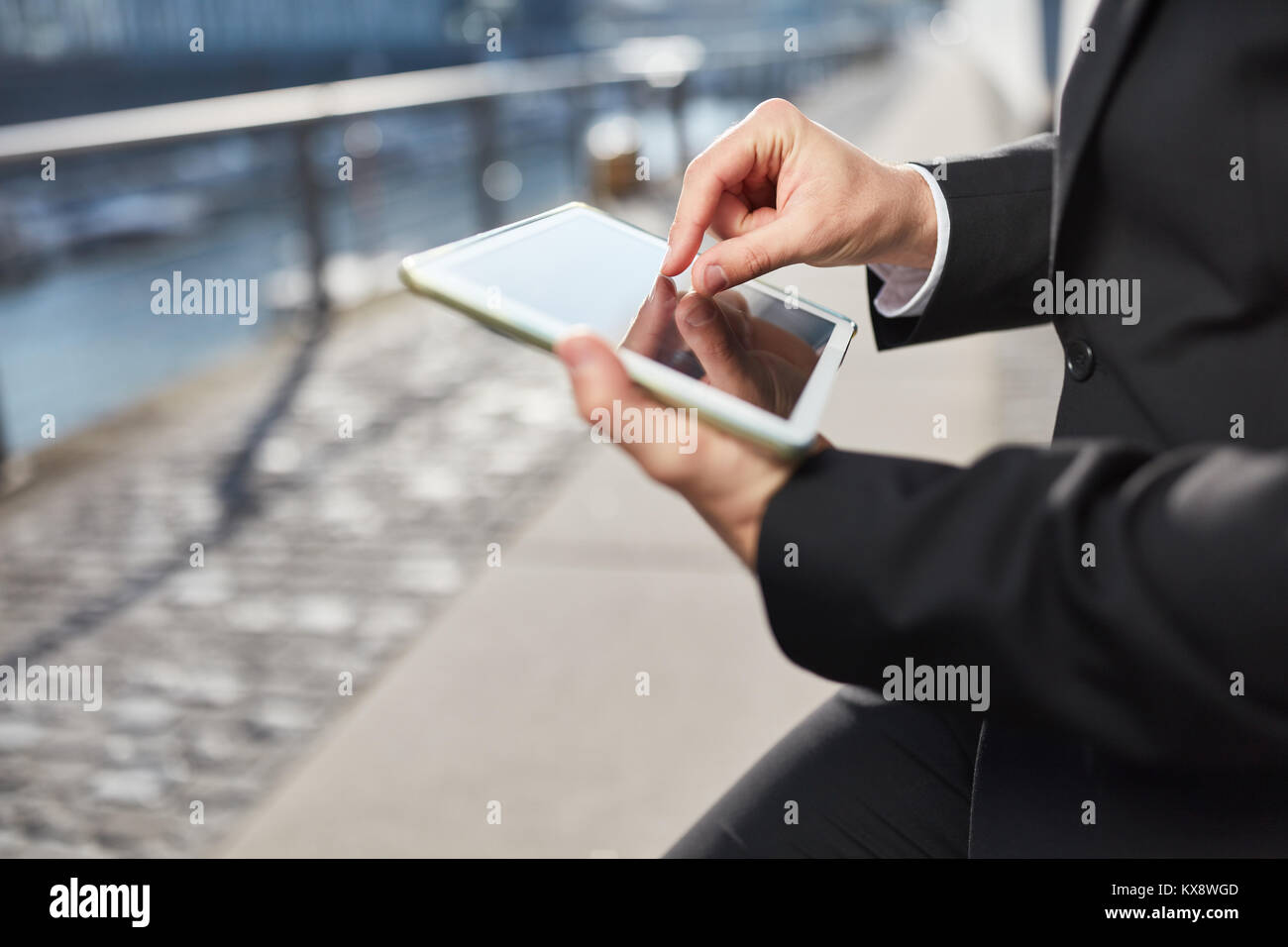 Business man operates the touch screen of a tablet computer outdoors