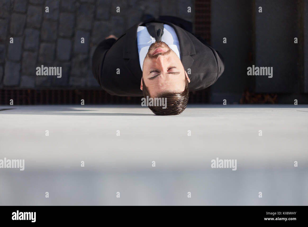 View from above of exhausted businessman leaning against a brick wall Stock Photo