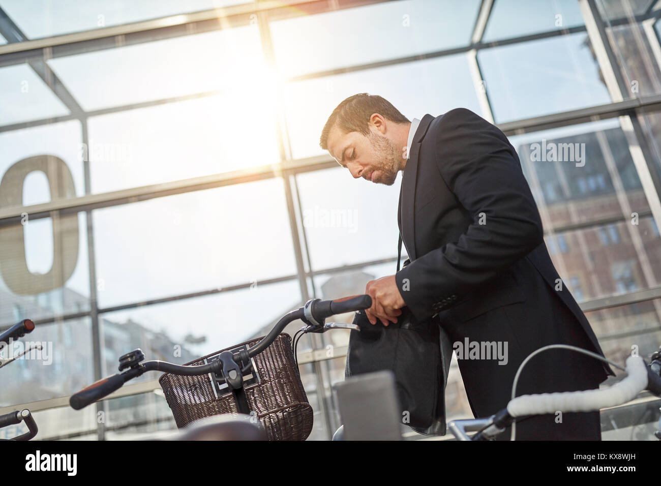Businessman as commuter and cyclist looks for the bicycle key Stock
