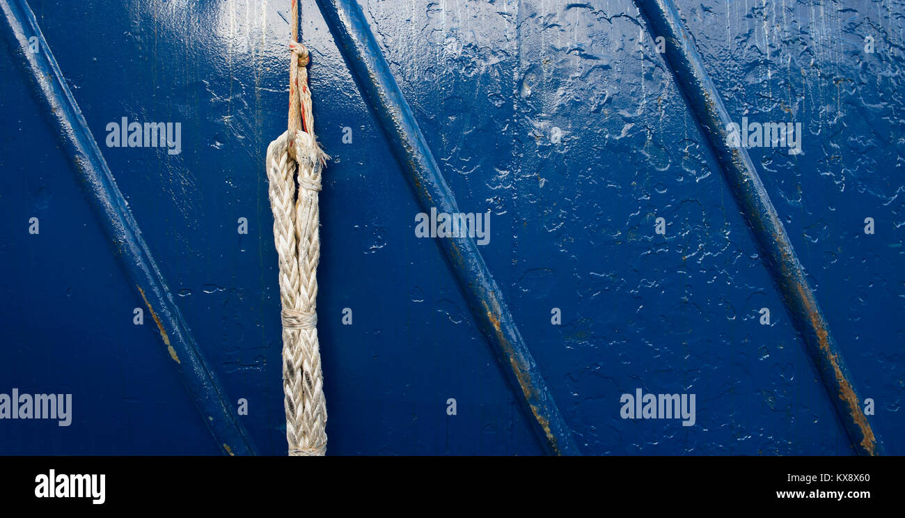A up close photo of a used boat rope and a blue painted metal rough surface texture Stock Photo